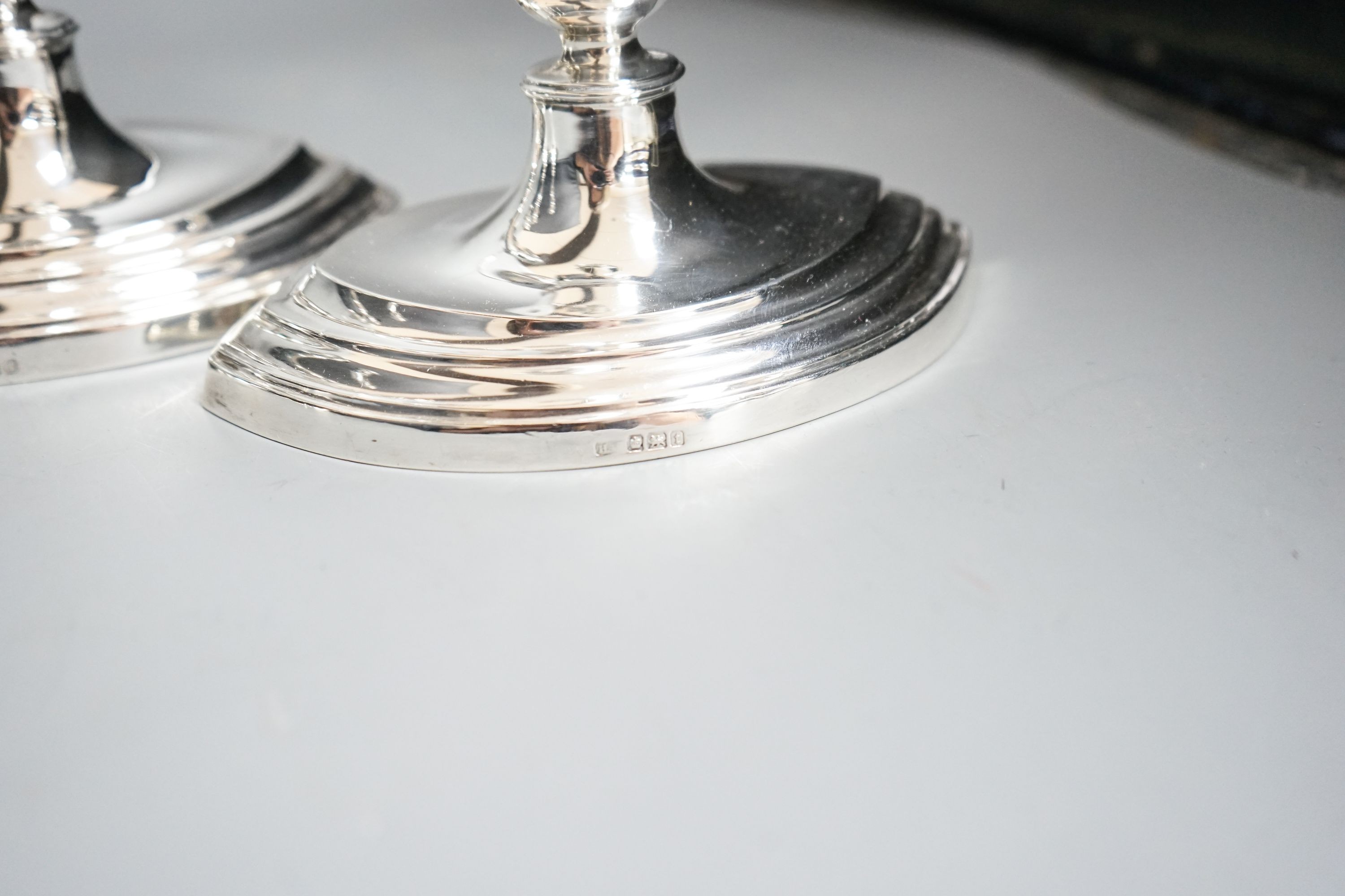 A set of four George V silver oval candlesticks, Atkin Brothers, Sheffield, 1911, height 24.2cm, together with a later silver two branch, three light candelabrum, height 35cm, all weighted.